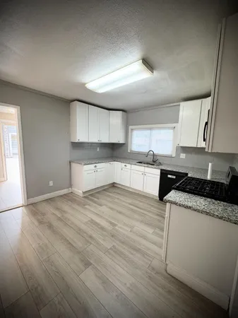 a kitchen with granite countertop white cabinets and a window
