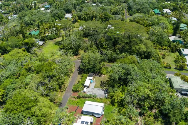 an aerial view of residential house with outdoor space and trees all around