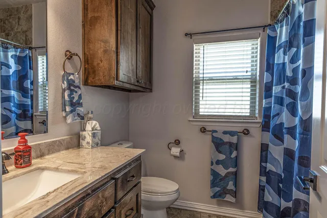 a bathroom with a granite countertop sink a toilet and a mirror