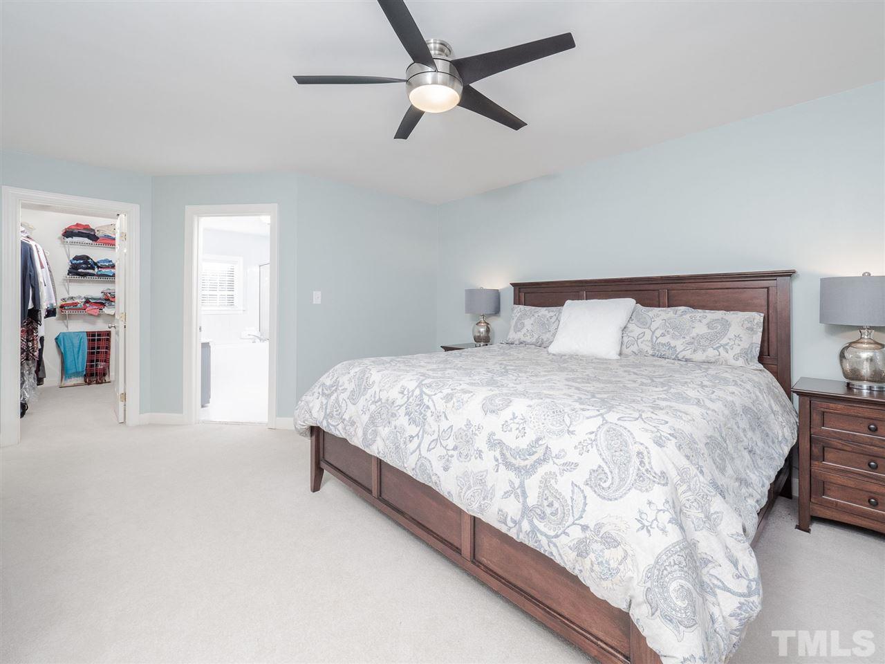 1003 Beringer Place Apex, NC 27502 - Photo 20 of 30 a bedroom with a large bed and a chandelier
