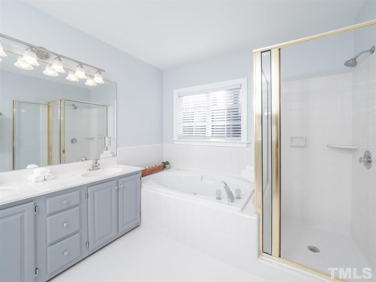 1003 Beringer Place Apex, NC 27502 - Photo 22 of 30 a bathroom with a tub a sink double vanity and mirror