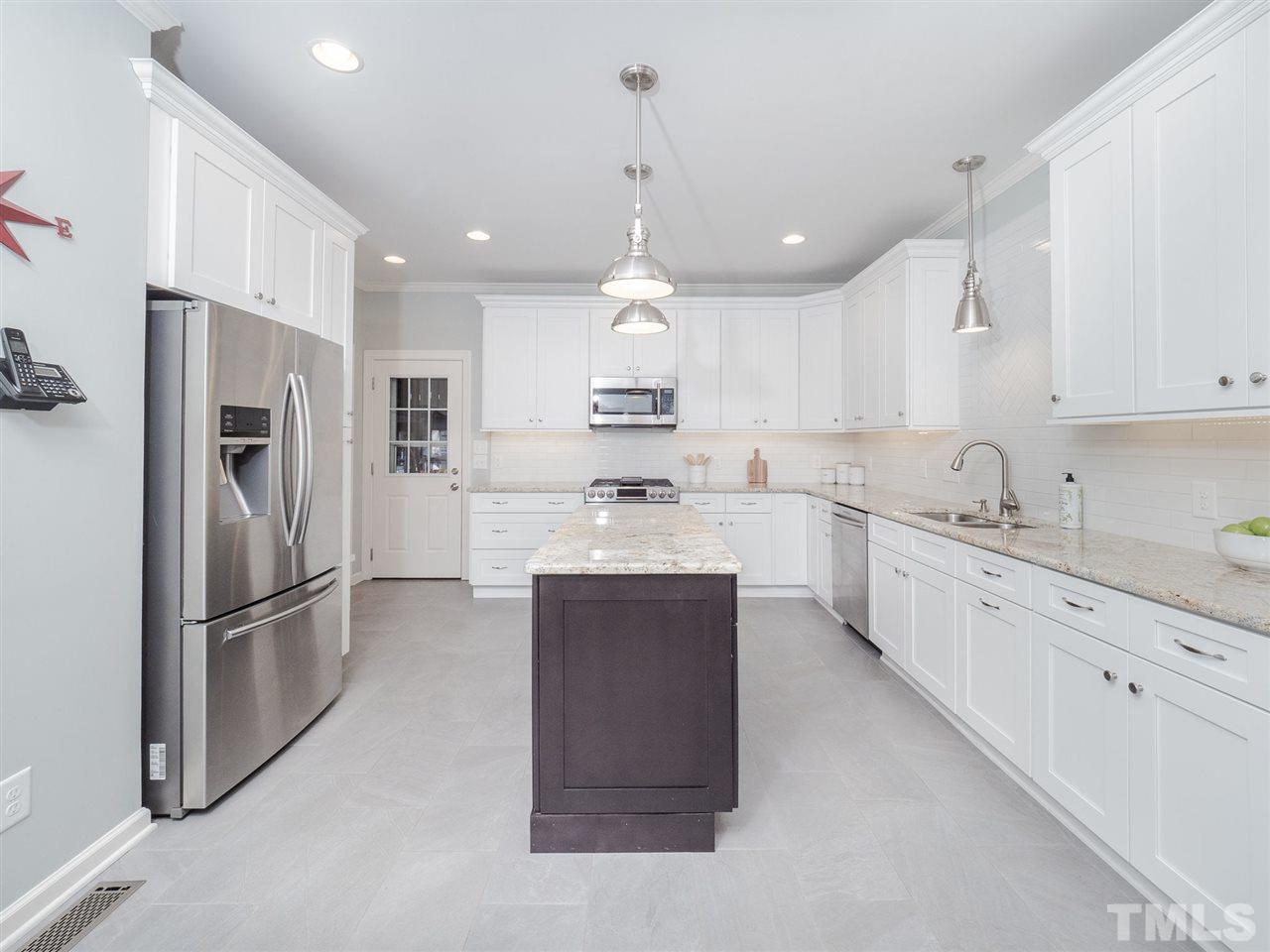 1003 Beringer Place Apex, NC 27502 - Photo 8 of 30 a large kitchen with stainless steel appliances kitchen island granite countertop a refrigerator oven a sink dishwasher and white cabinets with wooden floor