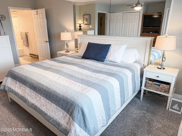 a bedroom with a bed and large mirror on the dresser