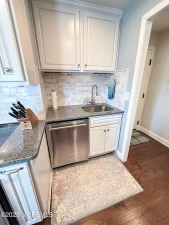 a kitchen with granite countertop a sink a stove and cabinets