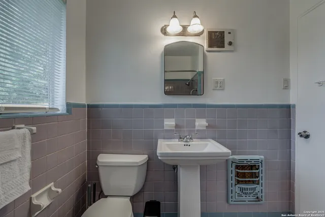 a bathroom with a toilet a sink and mirror