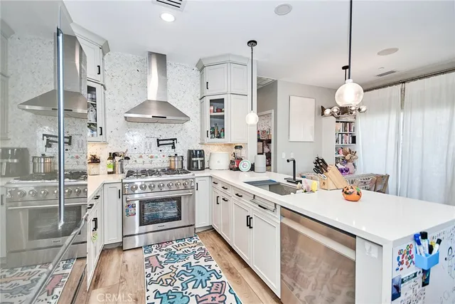 a kitchen that has a lot of white cabinets and stainless steel appliances