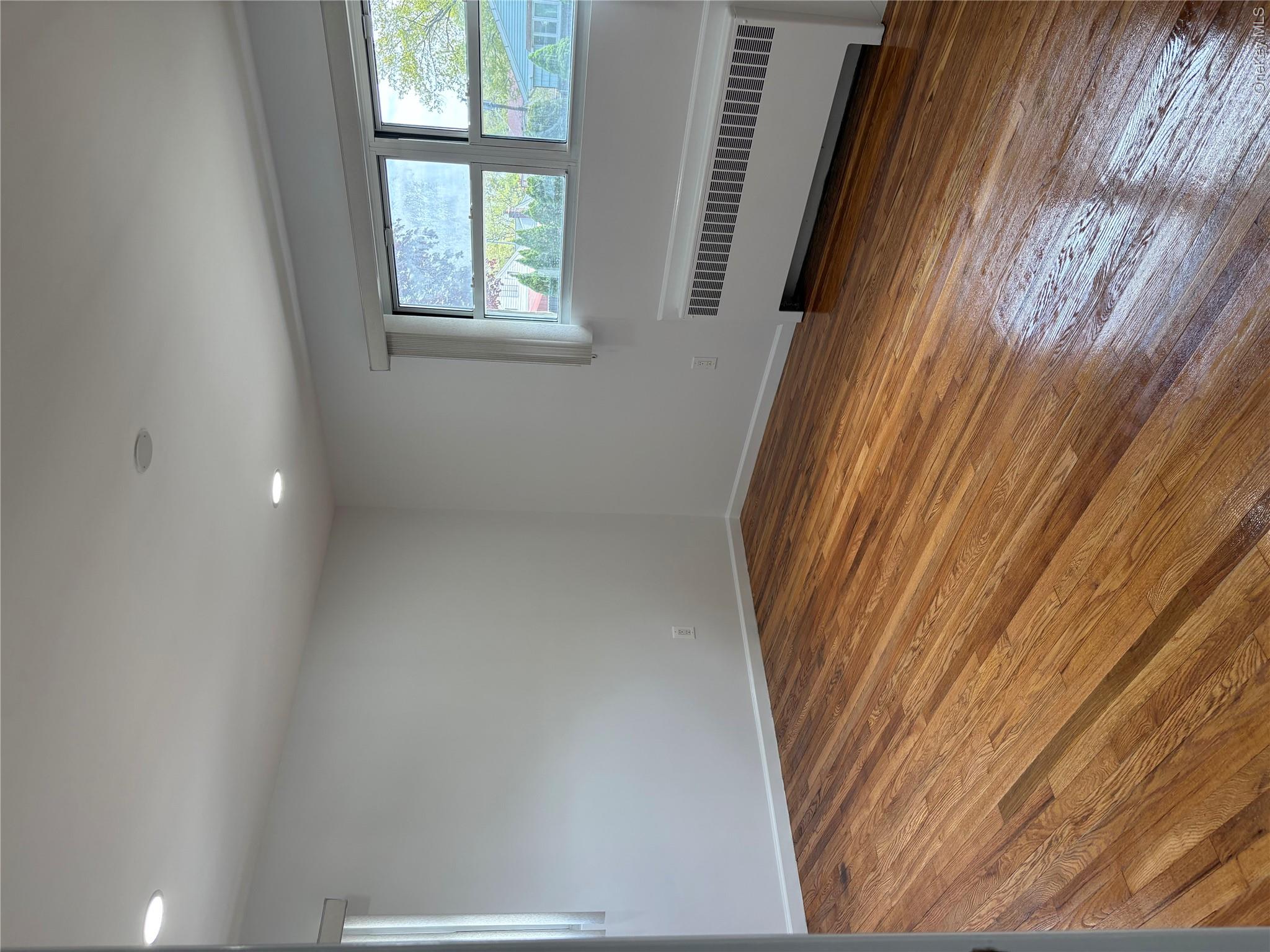 2262 Leighton Road Elmont, NY 11003 - Photo 2 of 12 an empty room with wooden floor and windows