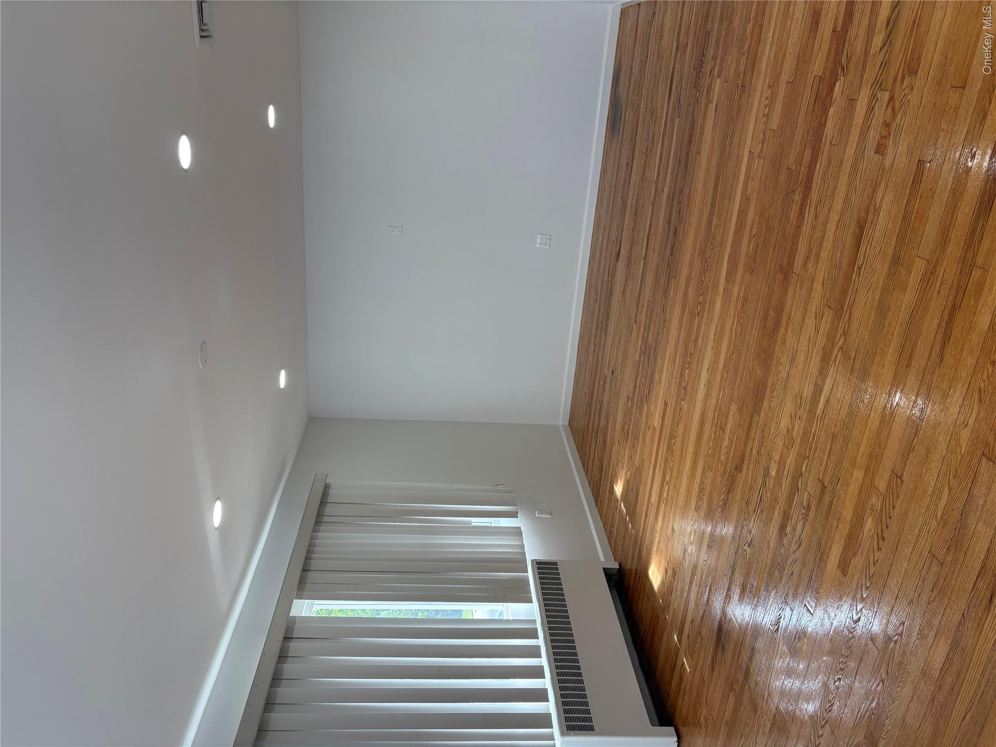 2262 Leighton Road Elmont, NY 11003 - Photo 5 of 12 a view of an empty room with wooden floor and a window