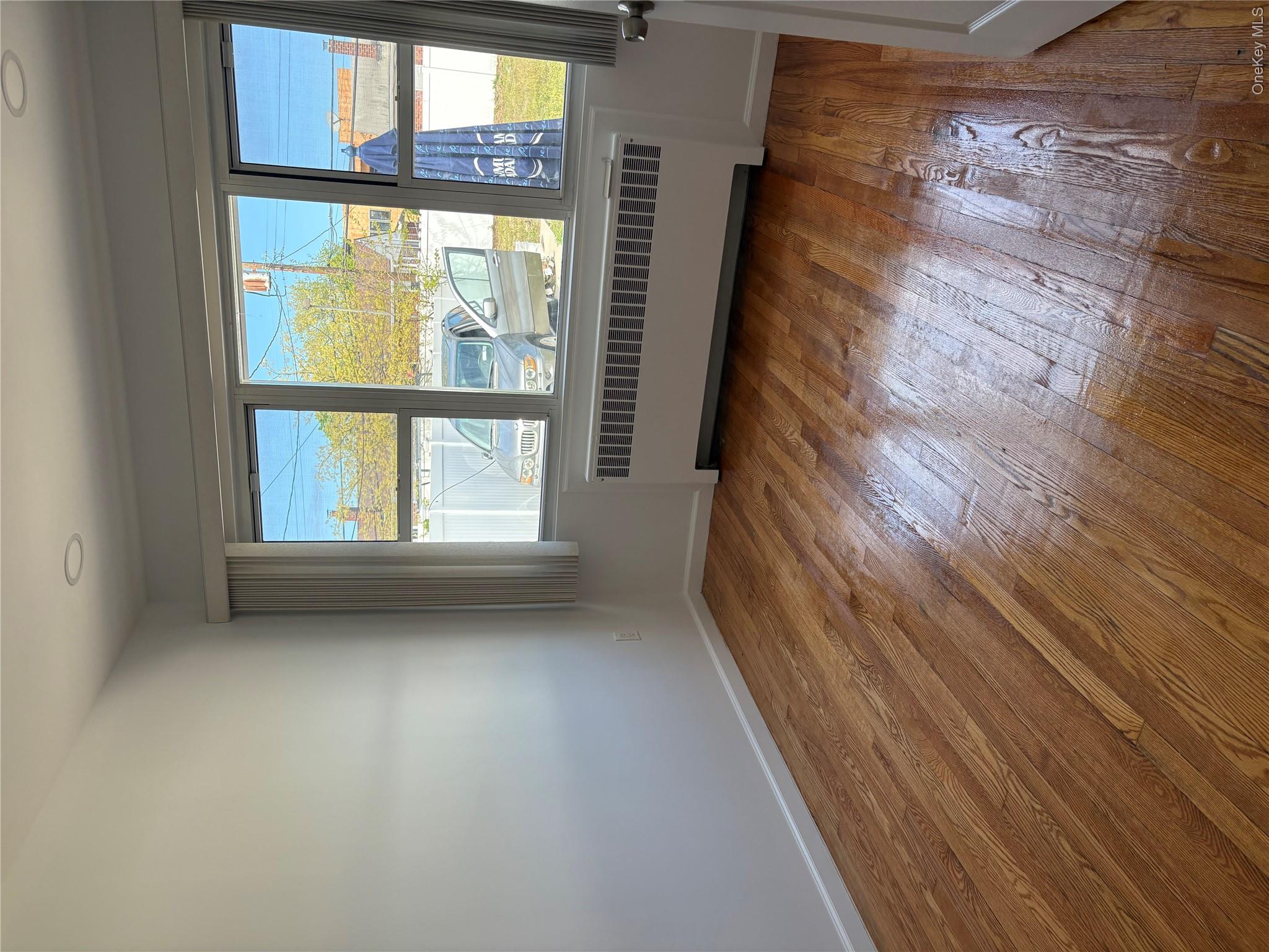 2262 Leighton Road Elmont, NY 11003 - Photo 6 of 12 a view of an empty room with wooden floor and a window