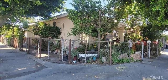 a view of a barn with large trees and a wooden fence
