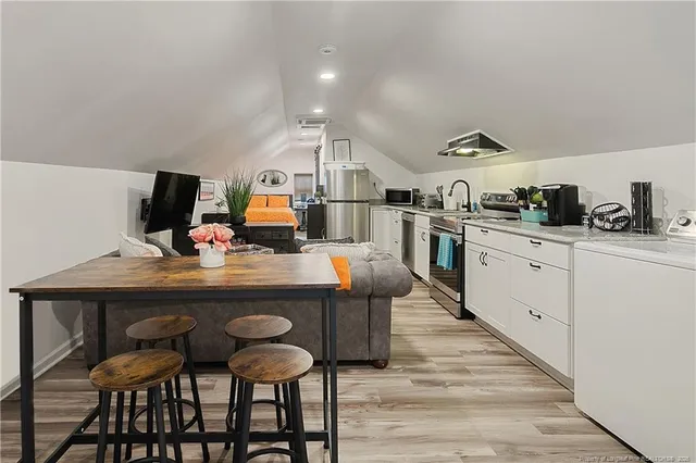 a kitchen with stainless steel appliances a table and chairs in it