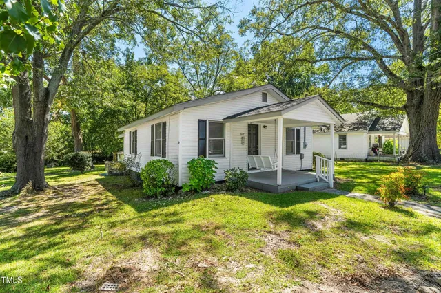 a view of a house with a big yard plants and large trees