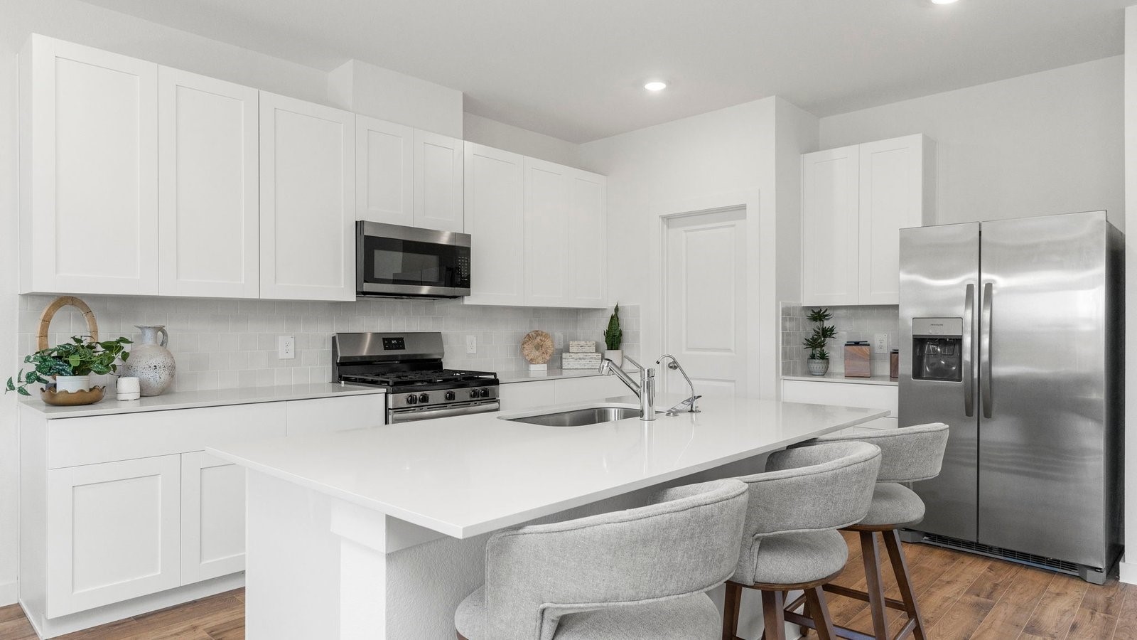 3531 Blue Mockingbird Street Katy, TX 77494 - Photo 7 of 41 a kitchen with a sink a microwave a refrigerator and chairs