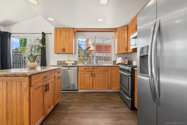 a kitchen with stainless steel appliances granite countertop a refrigerator a sink dishwasher a stove and white countertops with wooden floor