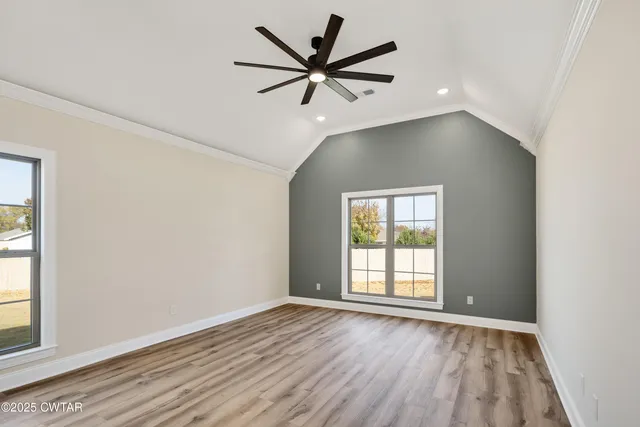 an empty room with wooden floor fan and windows
