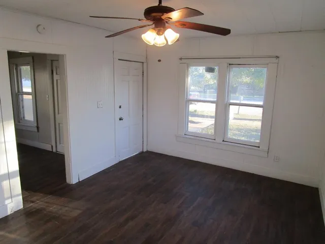 an empty room with wooden floor and windows