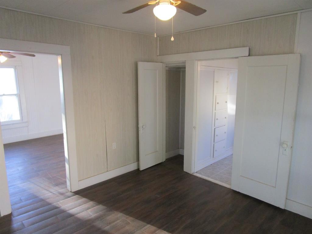 220 Southwest 5th Street Hamlin, TX 79520 - Photo 22 of 28 an empty room with wooden floor chandelier fan and windows