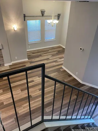 an empty room with wooden floor chandelier and windows