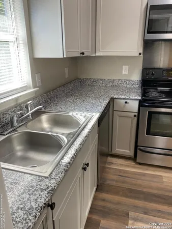 a kitchen with granite countertop a sink and stainless steel appliances