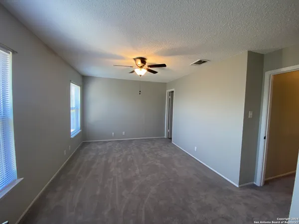 an empty room with ceiling fan and window