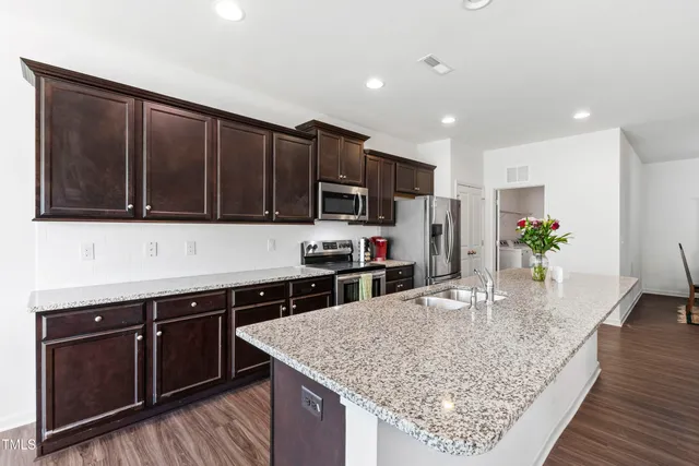 a kitchen with stainless steel appliances granite countertop a stove a sink dishwasher a microwave oven and a refrigerator with wooden floor