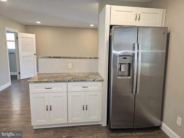 a kitchen with granite countertop a refrigerator and a sink