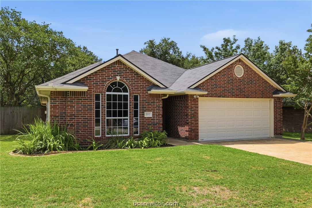 1707 Beaver Pond Court Bryan, TX 77807 - Photo 3 of 33 Brick exterior featuring a two-car garage, arched window, circular gable vent, and established landscaping