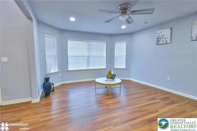 a kitchen with stainless steel appliances granite countertop a refrigerator a microwave oven a sink dishwasher and white cabinets with wooden floor