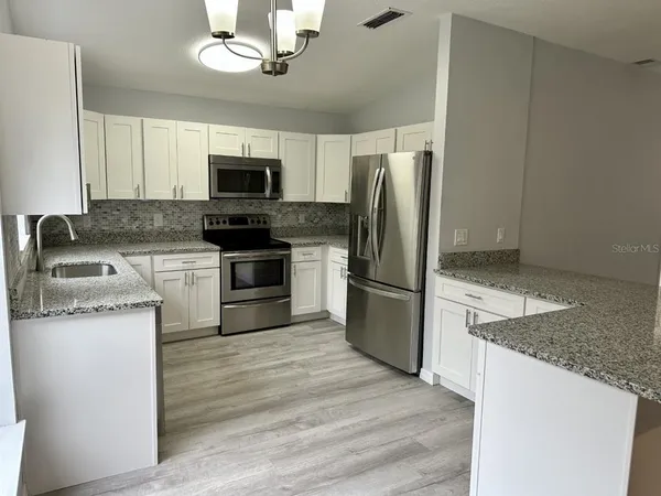 a kitchen with stainless steel appliances granite countertop a refrigerator stove and microwave