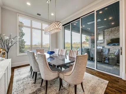 a dining room with furniture large windows and wooden floor