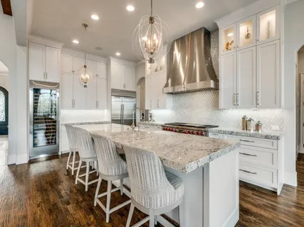 a kitchen with stainless steel appliances granite countertop a stove top oven a refrigerator a sink and a island with wooden floor