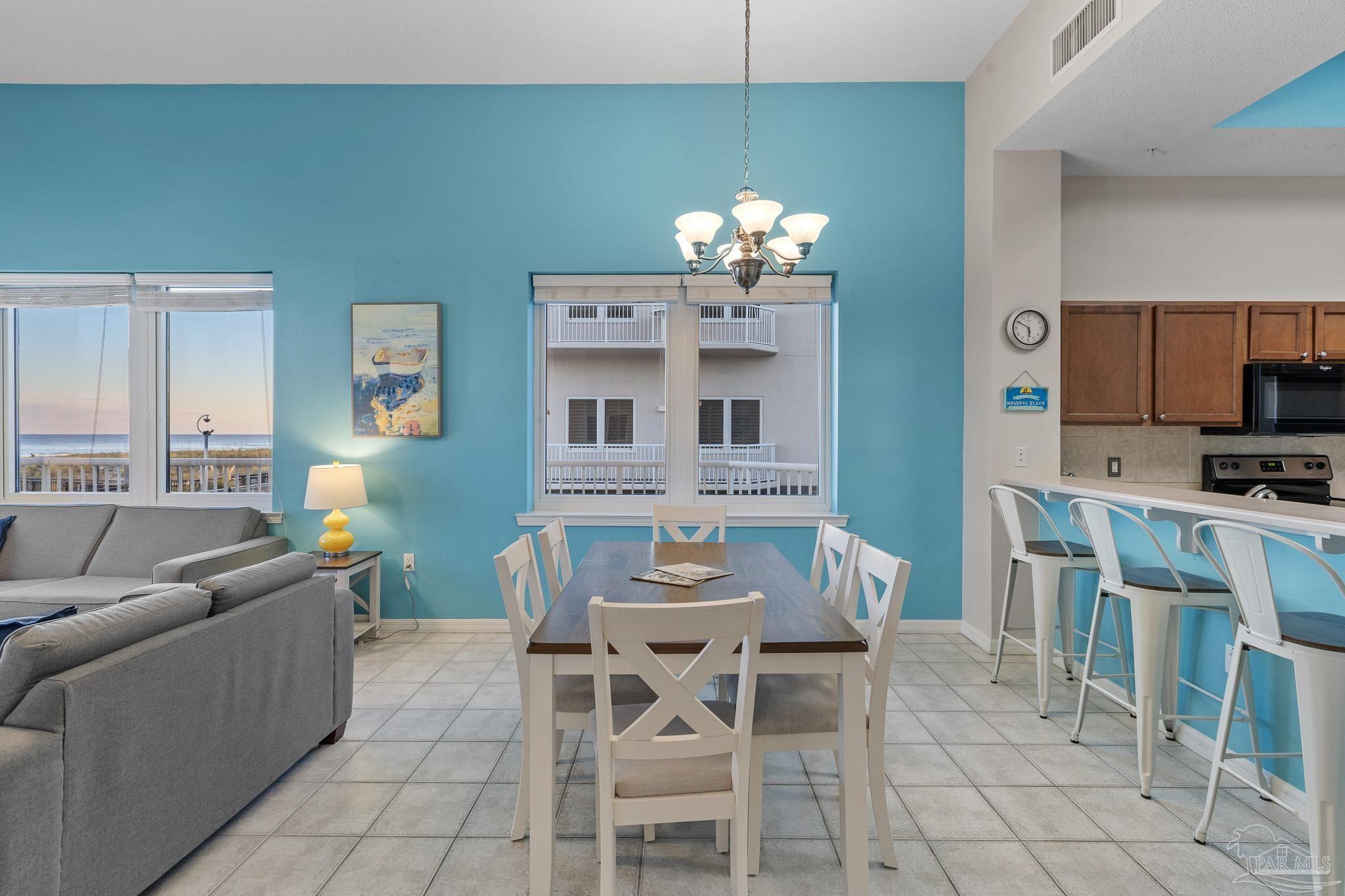 8577 Gulf Boulevard, Unit 105 Navarre Beach, FL 32566 - Photo 11 of 38 a view of a dining room with furniture a kitchen and chandelier