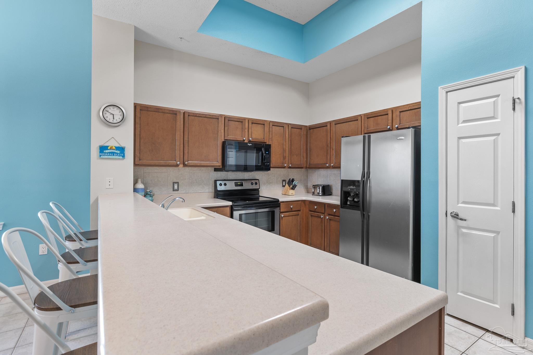 8577 Gulf Boulevard, Unit 105 Navarre Beach, FL 32566 - Photo 10 of 38 a kitchen with granite countertop stainless steel appliances a refrigerator a stove top oven a sink a granite counter tops and a view of living room