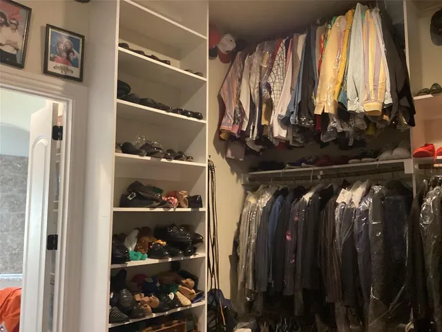 a view of walk in closet with clothes and shoes