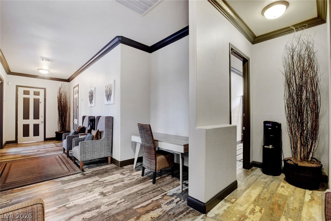 555 East Silverado Ranch Boulevard, Unit 2124 Las Vegas, NV 89183 - Photo 44 of 47 Enter into a welcoming hallway with rich crown molding and textured flooring, offering a glimpse of a private workspace.