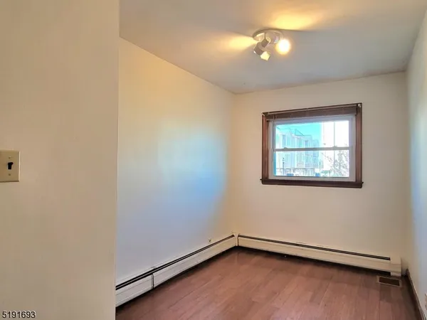 a view of an empty room with wooden floor and fan