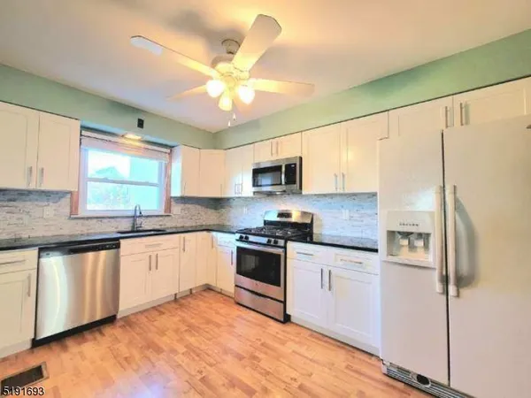 a kitchen with stainless steel appliances granite countertop a stove top oven a sink a refrigerator with a dining table and chairs