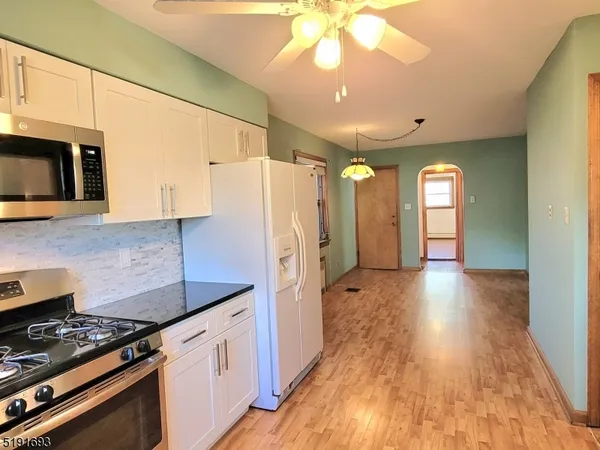 a kitchen with stainless steel appliances granite countertop a refrigerator a stove and a wooden floors