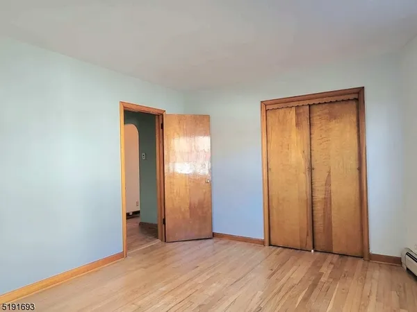 an empty room with wooden floor and closet area