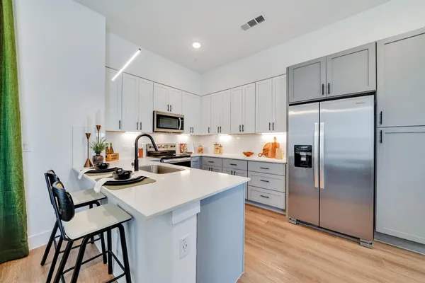 a kitchen with a refrigerator a stove a sink and chairs