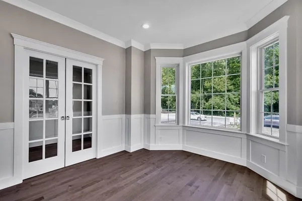 a view of an empty room with wooden floor and windows