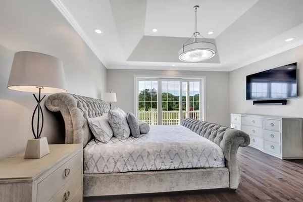 a bedroom with a large bed and a flat tv screen on dresser