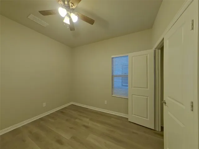 a view of empty room with wooden floor and fan