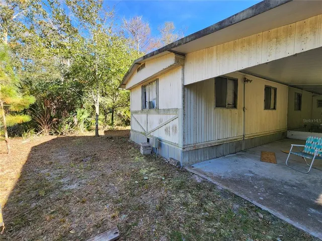 a view of a house with a yard tree and a wooden fence