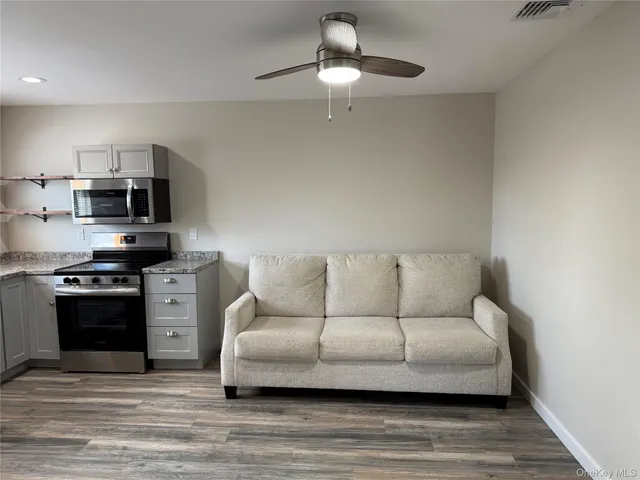 a living room with stainless steel appliances kitchen island granite countertop a couch and a stove