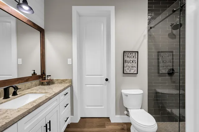 a bathroom with a granite countertop toilet sink and mirror