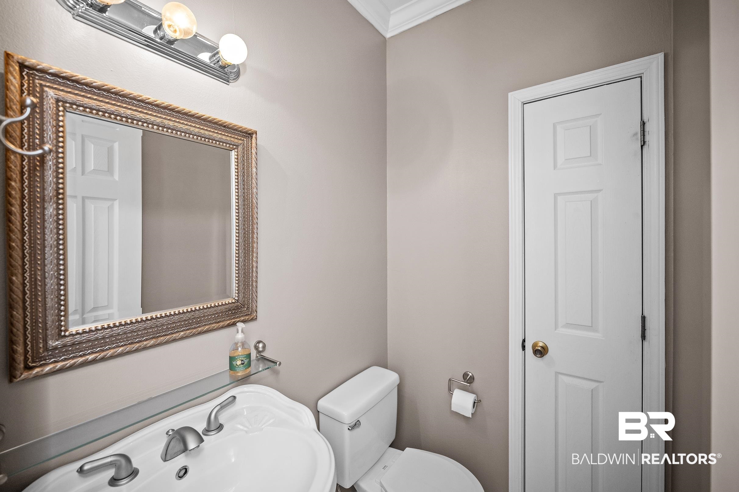 197 Morning Ridge Road Monroeville, AL 36460 - Photo 33 of 51 Powder room featuring a decorative framed mirror, three-bulb vanity light fixture, and a white pedestal sink with dual-handle faucet