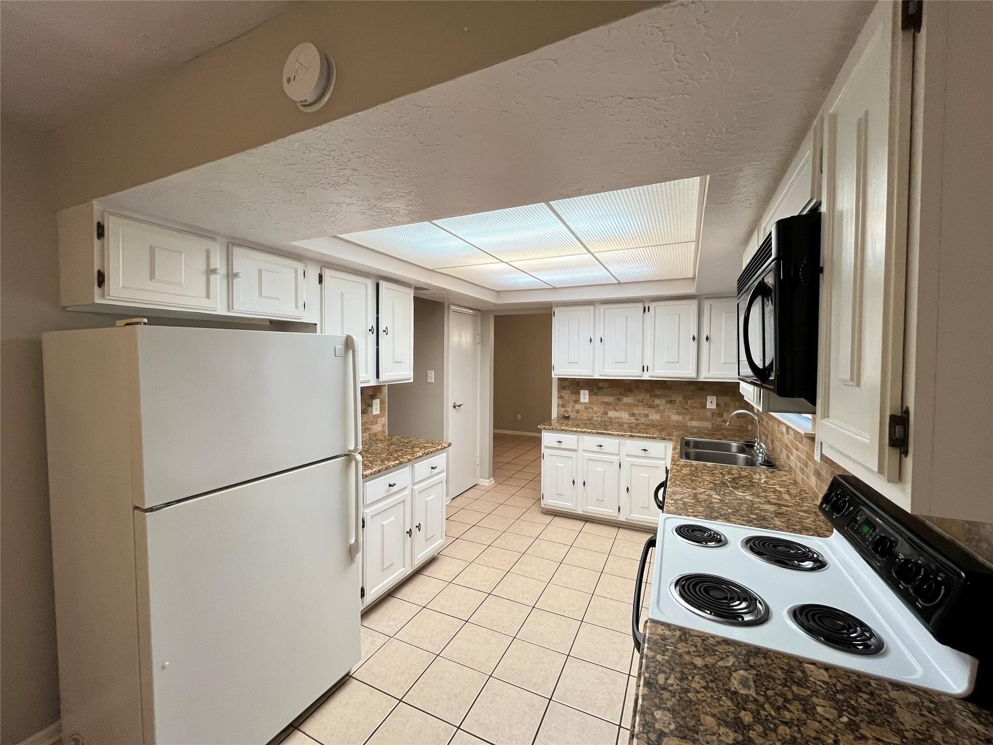 17 Briervine Court Spring, TX 77381 - Photo 5 of 19 a kitchen with stainless steel appliances granite countertop a refrigerator sink and white cabinets