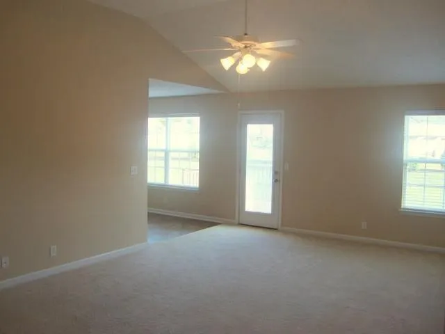 an empty room with chandelier fan and windows