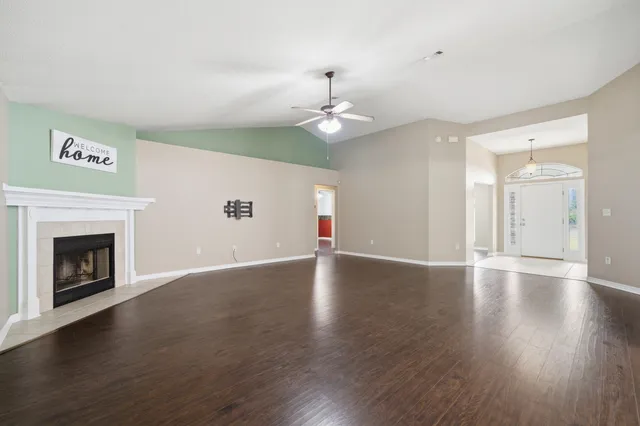 a view of an empty room with window and wooden floor